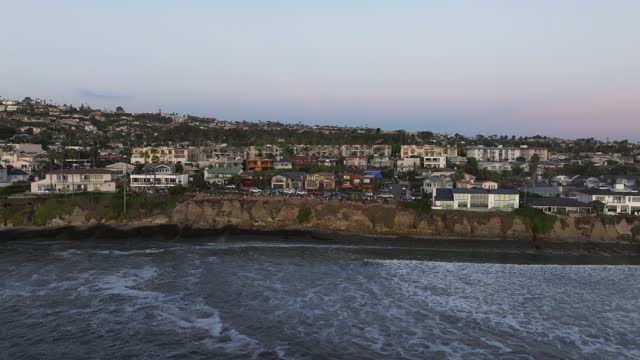 Low aerial view of the cliffs, the surf and the ocean at Bird Rock.