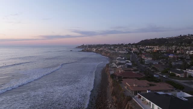 Aerial view of the cliffs, the surf and the ocean at Bird Rock, with surfers out.