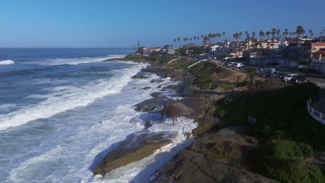 Low aerial view of the cliffs, the surf and palm trees at Beach Barber Tract.