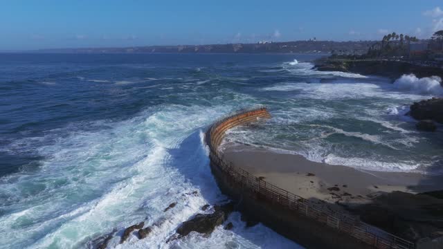 Low aerial view of the beach, the surf and the ocean at La Jolla Village.