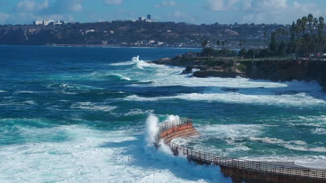 Aerial view of the cliffs, the surf and palm trees at La Jolla Village.