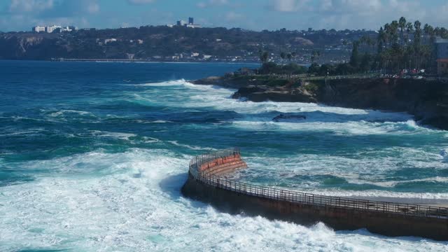 Aerial view of the cliffs, the surf and palm trees at La Jolla Village.