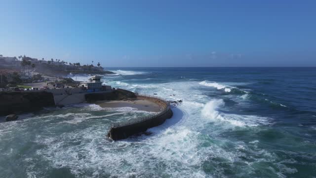 Aerial view of the cliffs, the surf and palm trees at La Jolla Village.