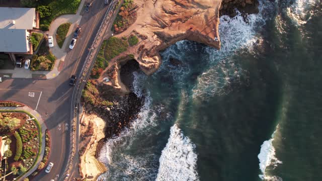 Aerial view of the cliffs, the surf and the ocean at Sunset Cliffs, with people walking.
