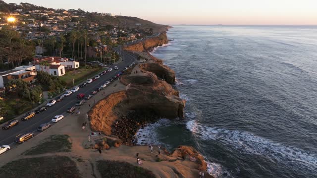 Aerial view of the cliffs, the surf and palm trees at Sunset Cliffs, with people walking.