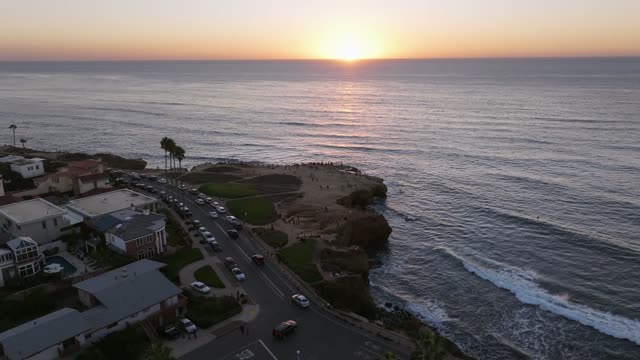 Aerial view of the cliffs, palm trees and the ocean at Sunset Cliffs, with a crowd gathered.
