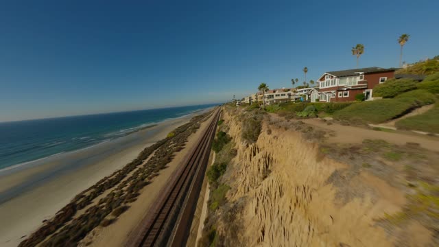 Low aerial view of the cliffs, palm trees and the ocean in Del Mar.