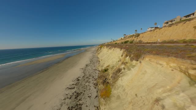 Low aerial view of the cliffs, the ocean and homes in Del Mar.