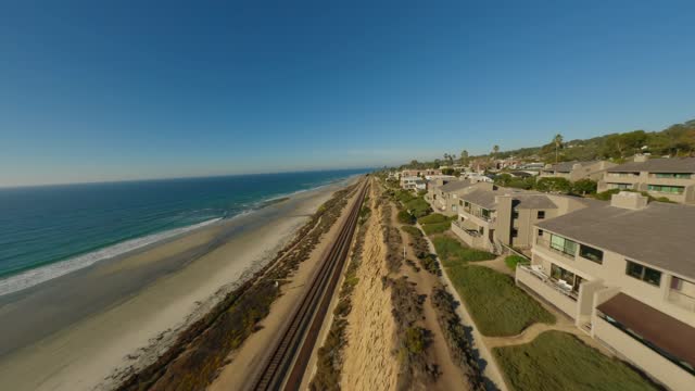 Low aerial view of the cliffs, the ocean and homes in Del Mar.