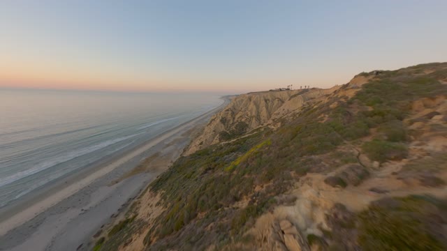 Low aerial view of the cliffs, the ocean and the beach at Black’s Beach.