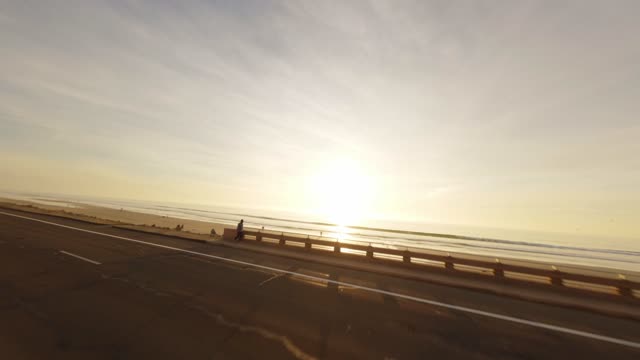 Low aerial view of the beach, the surf and the ocean in Carlsbad, with people walking.