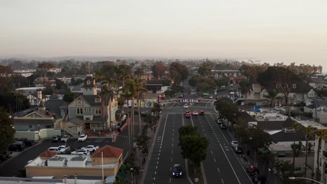 Low aerial view of the downtown streets, palm trees and homes in Carlsbad, with people walking.