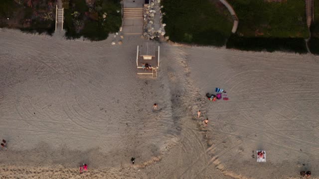 Aerial view of the beach and open country in Carlsbad, with people walking.