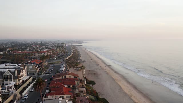 Aerial view of the beach, palm trees and the ocean in Carlsbad, with people walking.