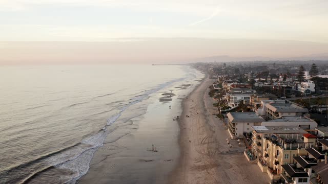 Aerial view of the beach, the ocean and homes in Carlsbad, with people walking.