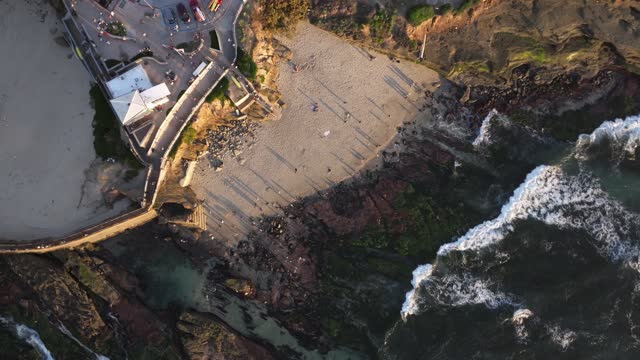 Aerial view of the beach, the surf and the ocean at La Jolla Cove, with people walking.