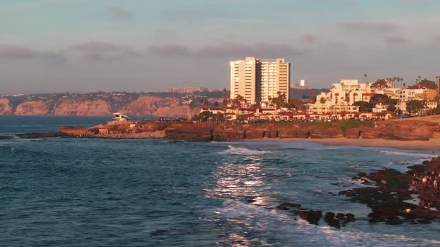 Low aerial view of the cliffs, the surf and the ocean at La Jolla Cove.