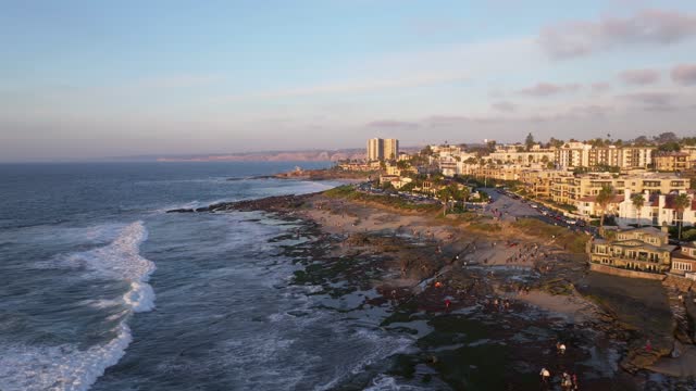 Aerial view of the beach, the surf and the ocean at La Jolla Cove, with people walking.