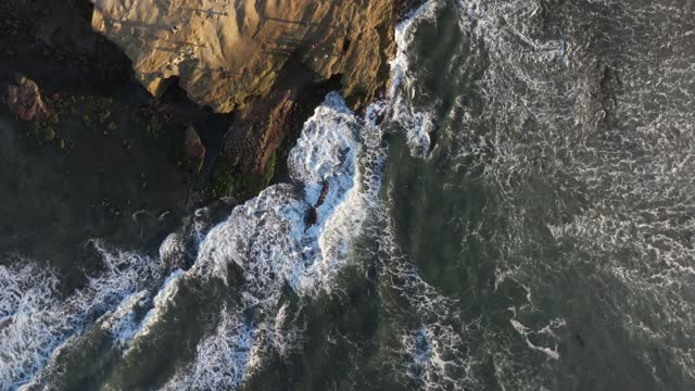 Aerial view of the cliffs, the surf and the ocean at Sunset Cliffs.