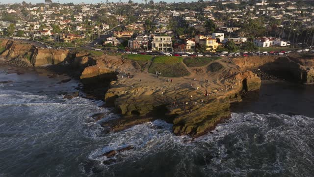 Aerial view of the cliffs, the surf and the ocean at Sunset Cliffs, with people walking.