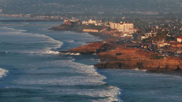 Aerial view of the cliffs, the surf and the ocean at Sunset Cliffs, with people walking.