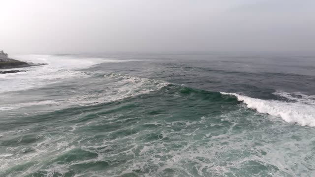 Low aerial view of the cliffs, the surf and the ocean at La Jolla Cove.