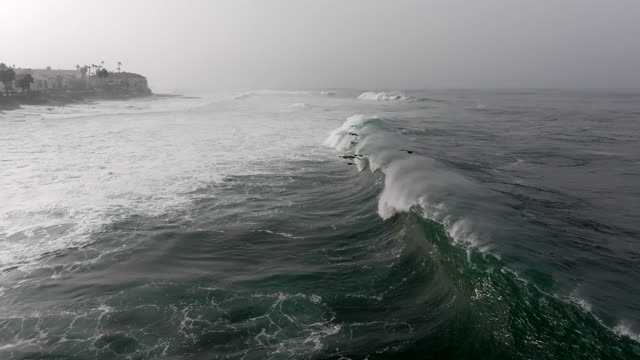 Low aerial view of the cliffs, the surf and the ocean at La Jolla Cove.