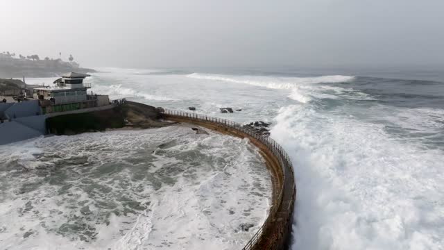 Low aerial view of the cliffs, the surf and the ocean at La Jolla Cove.