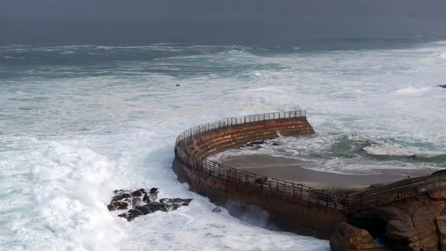 Low aerial view of the cliffs, the surf and the ocean at La Jolla Cove.