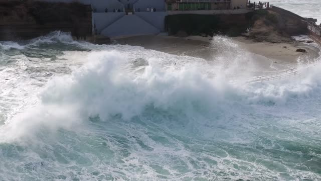 Low aerial view of the cliffs, the surf and the ocean at La Jolla Cove.