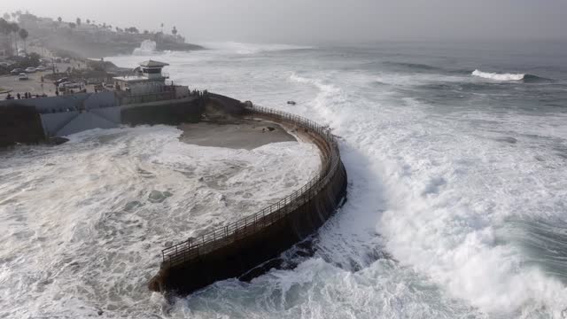 Aerial view of the beach, the surf and palm trees at La Jolla Cove, with people walking.