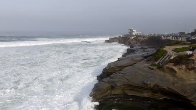 Low aerial view of the cliffs, the surf and the ocean at La Jolla Cove.