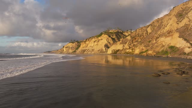 Low aerial view of the beach, the surf and the ocean at Black’s Beach.