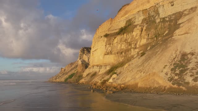 Low aerial view of the cliffs, the ocean and the beach at Black’s Beach.