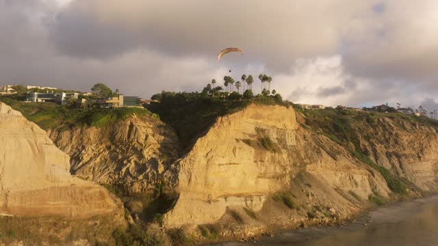 Low aerial view of the cliffs, palm trees and homes at Black’s Beach.