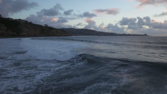 Low aerial view of the beach, the surf and the pier at Black’s Beach.