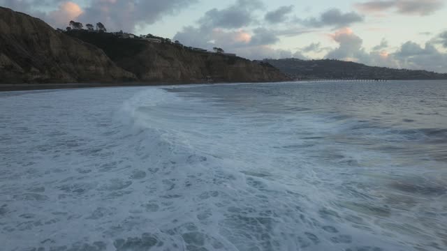 View from the water of the beach, the surf and the pier at Black’s Beach.