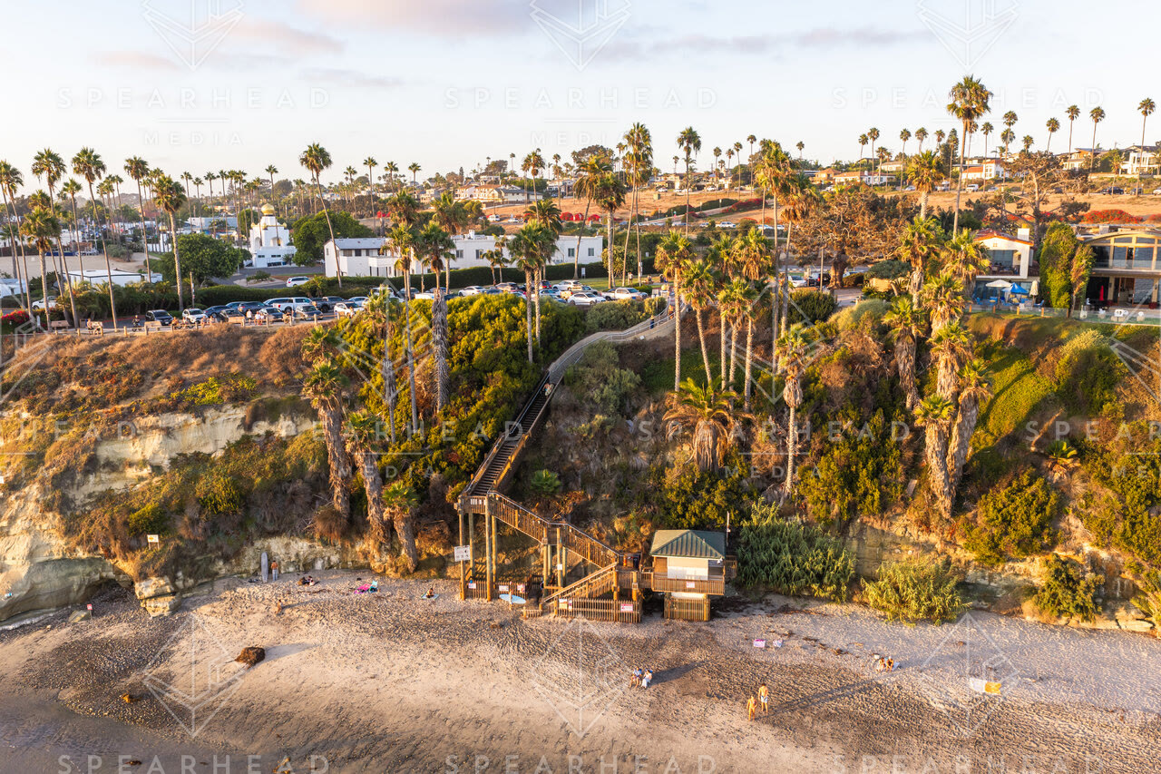 Aerial view of the cliffs, palm trees and the ocean at Swamis, with people walking.