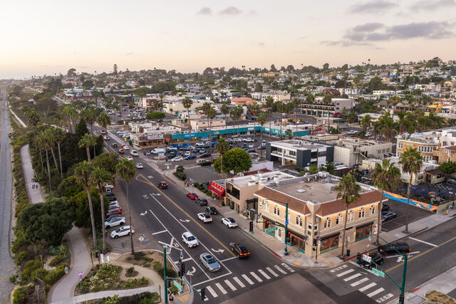 Aerial view of the downtown streets, palm trees and homes in Cardiff, with people walking.