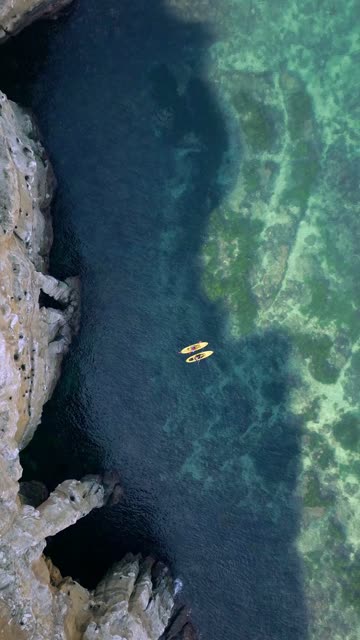 Aerial view of the cliffs, boats and the ocean at La Jolla Cove, with paddlers on the water.