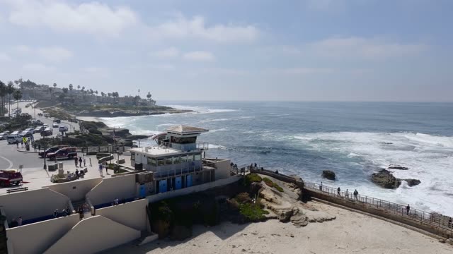 Aerial footage of the lifeguard tower, cliffs and coastline at La Jolla Cove in La Jolla | Drone Video