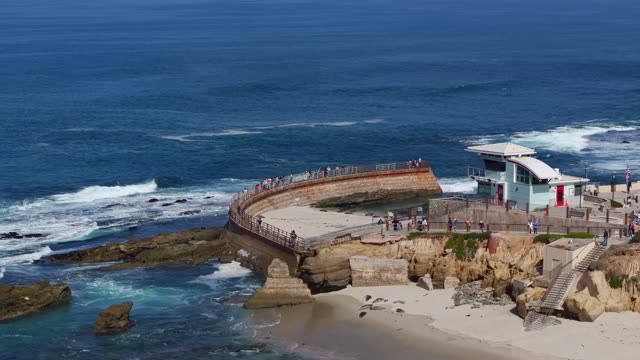 Aerial footage of visitors walking the curved sea wall at Children's Pool in La Jolla | Drone Video