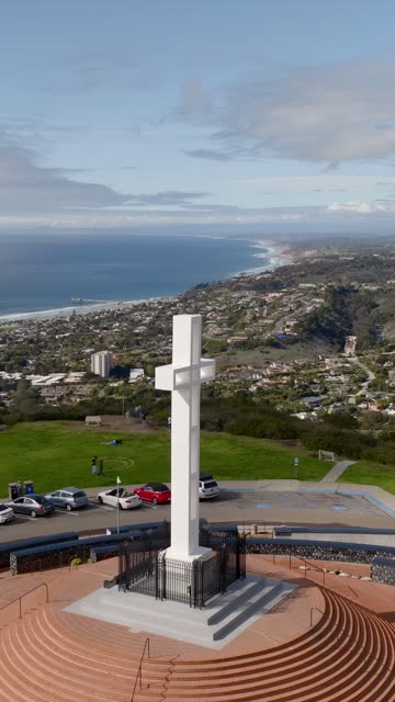 Aerial view of a park, the ocean and homes at Mount Soledad, with people walking.