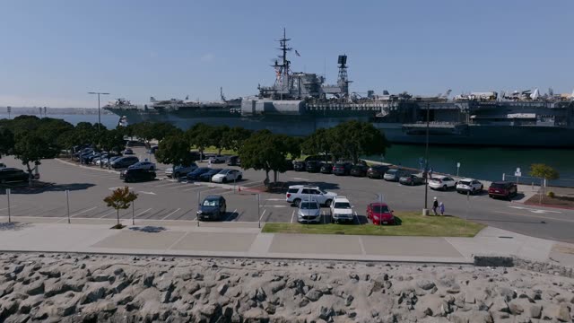 Aerial footage of the USS Midway Museum and flight deck along the Embarcadero waterfront in Downtown San Diego with skyline and bay views | Drone Video
