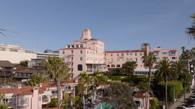 Aerial footage of the La Valencia Hotel, known as the Pink Lady, overlooking palm trees and village rooftops in La Jolla | Drone Video