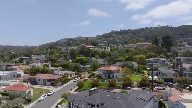 Aerial footage flying over rooftops, palm trees and Mount Soledad hillside homes in the Village of La Jolla | Drone Video
